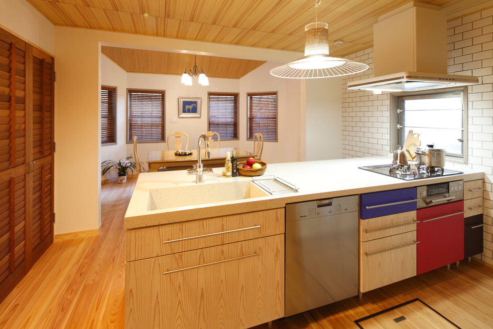 Offene Landhaus Küche mit integriertem Waschbecken, braunem Holzboden, flächenbündigen Schrankfronten und hellen Holzschränken in Sonstige