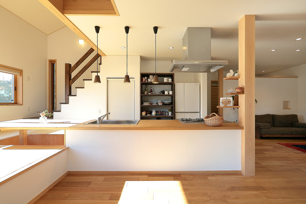 Example of a zen single-wall medium tone wood floor and brown floor open concept kitchen design in Other with a single-bowl sink, wood countertops and brown countertops