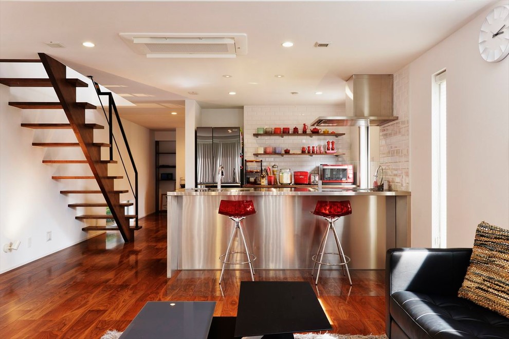コンテンポラリースタイルのおしゃれなキッチン (ステンレスカウンター、メタリックのキッチンパネル、シングルシンク、塗装フローリング、茶色い床) の写真