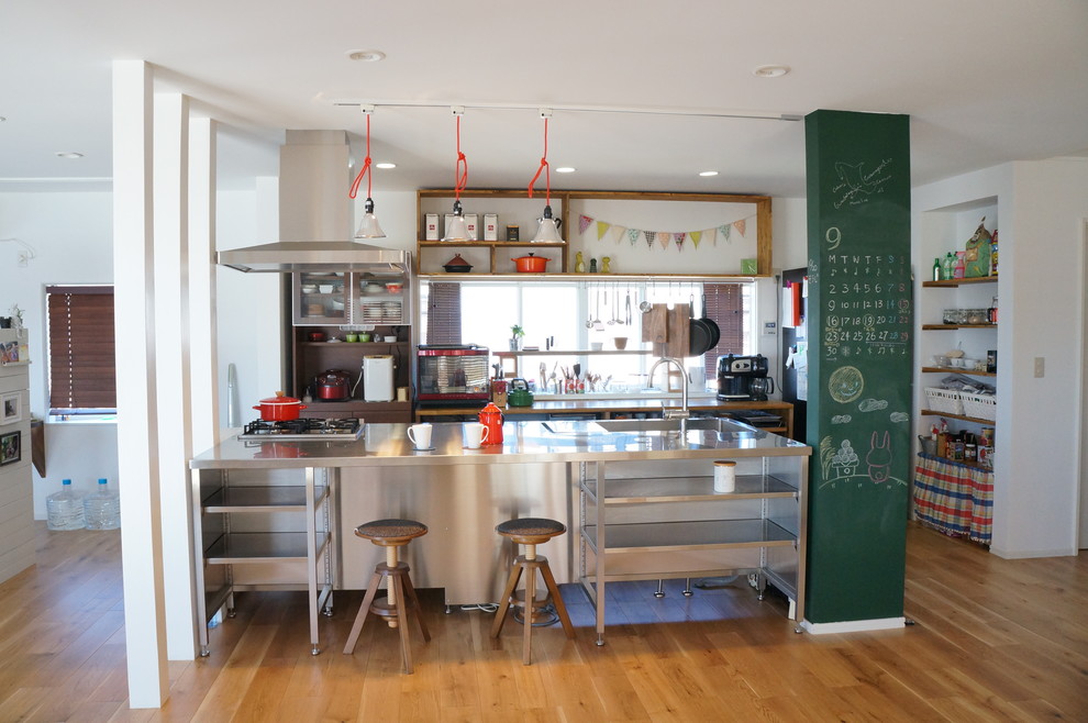 Exempel på ett industriellt kök, med en integrerad diskho, öppna hyllor, bänkskiva i rostfritt stål, mellanmörkt trägolv, en köksö och brunt golv