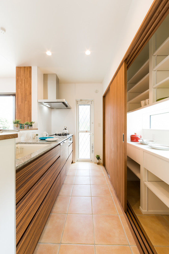 Lantlig inredning av ett kök, med en enkel diskho, klinkergolv i terrakotta och orange golv
