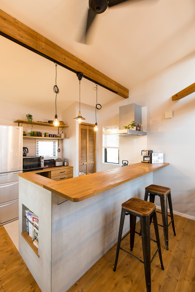 他の地域にあるインダストリアルスタイルのおしゃれなI型キッチン (中間色木目調キャビネット、淡色無垢フローリング、茶色いキッチンカウンター) の写真