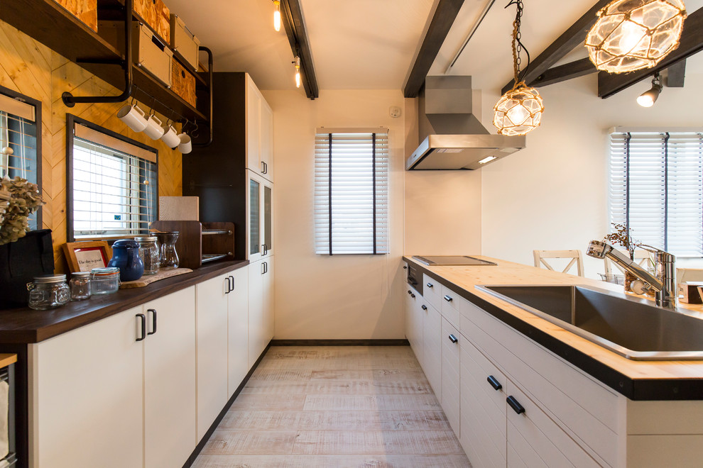 Modelo de cocina lineal urbana con fregadero de un seno, armarios con paneles lisos, puertas de armario blancas, encimera de madera, península y suelo blanco