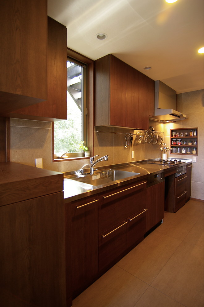 他の地域にあるミッドセンチュリースタイルのおしゃれなI型キッチン (一体型シンク、フラットパネル扉のキャビネット、中間色木目調キャビネット、ステンレスカウンター、茶色い床) の写真