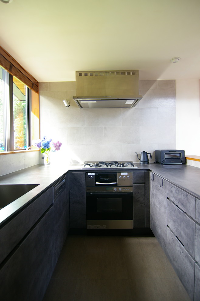 Bild på ett funkis grå grått kök, med en undermonterad diskho, grå skåp, grått stänkskydd, stänkskydd i porslinskakel, rostfria vitvaror, linoleumgolv och brunt golv