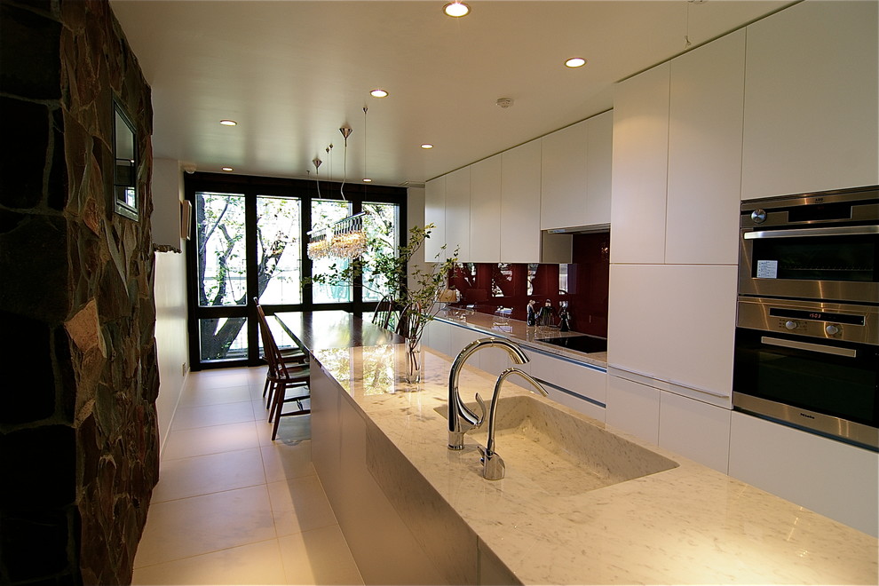 Idéer för ett modernt kök, med en integrerad diskho, släta luckor, vita skåp, marmorbänkskiva, en halv köksö och vitt golv