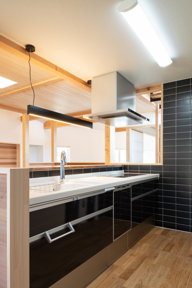 Bild på ett avskilt, stort funkis vit linjärt vitt kök, med en undermonterad diskho, släta luckor, svarta skåp, bänkskiva i koppar, svart stänkskydd, glaspanel som stänkskydd, mellanmörkt trägolv och brunt golv