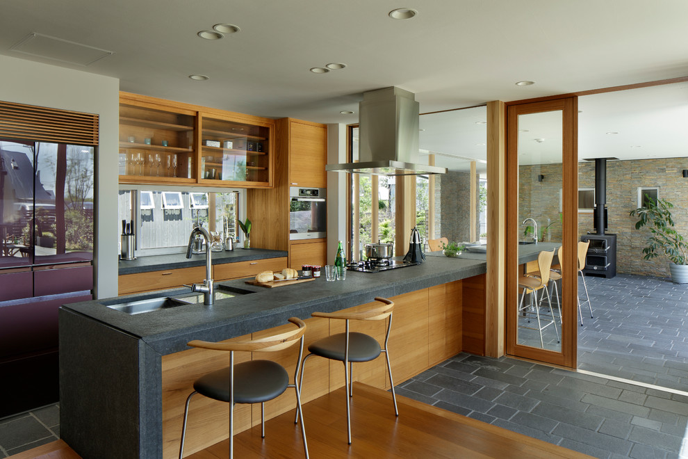Idee per una cucina minimal con lavello sottopiano, ante lisce, ante in legno scuro, paraspruzzi a finestra, penisola e pavimento grigio