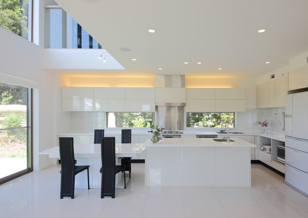 Inredning av ett modernt stort kök, med en undermonterad diskho, släta luckor, vita skåp, bänkskiva i koppar, vitt stänkskydd, stänkskydd i cementkakel, rostfria vitvaror, cementgolv, en köksö och vitt golv
