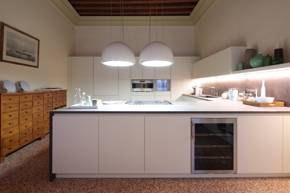 Идея дизайна: п-образная кухня в стиле фьюжн с монолитной мойкой, плоскими фасадами, белыми фасадами, серым фартуком и полуостровом