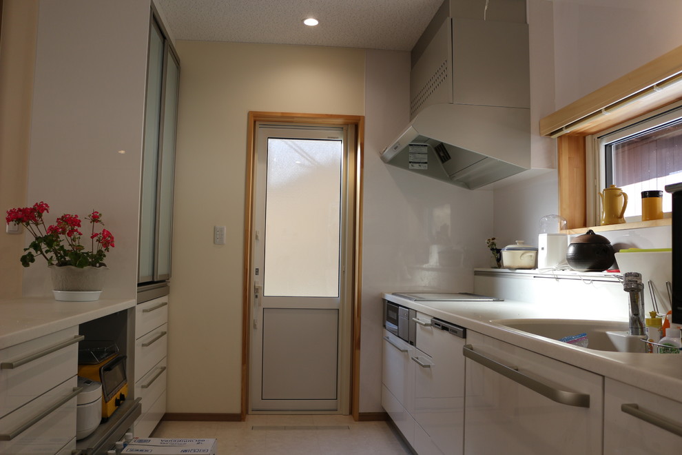 Immagine di una cucina moderna di medie dimensioni con lavello a vasca singola, ante di vetro, ante bianche, top in zinco, paraspruzzi bianco, elettrodomestici bianchi, pavimento in compensato, pavimento beige e top bianco