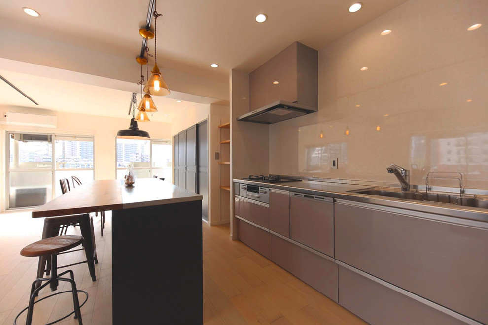 Idéer för stora minimalistiska linjära grått kök med öppen planlösning, med en undermonterad diskho, öppna hyllor, blå skåp, bänkskiva i rostfritt stål, vitt stänkskydd, glaspanel som stänkskydd, färgglada vitvaror, ljust trägolv, en köksö och vitt golv