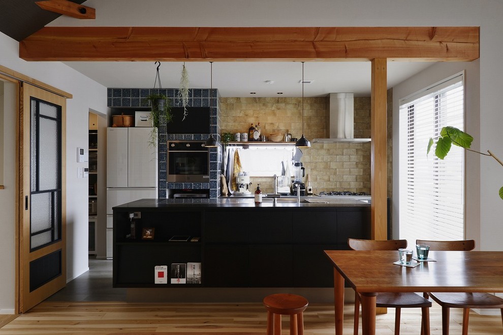 Inspiration for a galley medium tone wood floor and brown floor open concept kitchen remodel in Tokyo with a single-bowl sink, flat-panel cabinets, black cabinets and an island