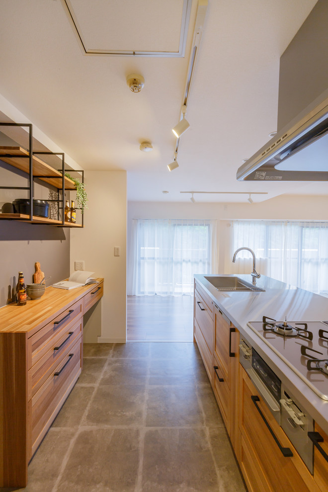 Exemple d'une cuisine linéaire scandinave avec un évier 1 bac, un placard à porte plane, des portes de placard marrons, un plan de travail en inox, un sol en ardoise, une péninsule, un sol gris et un plan de travail marron.