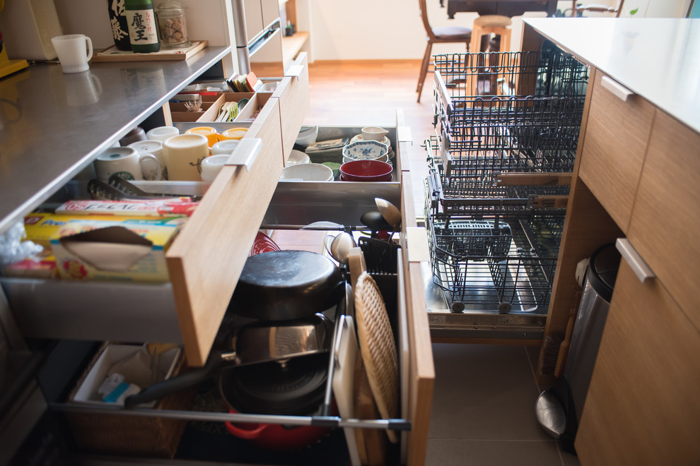 東京23区にある小さなコンテンポラリースタイルのおしゃれなキッチン (フラットパネル扉のキャビネット、淡色木目調キャビネット、ステンレスカウンター、木材のキッチンパネル、黒い調理設備、無垢フローリング、茶色い床) の写真