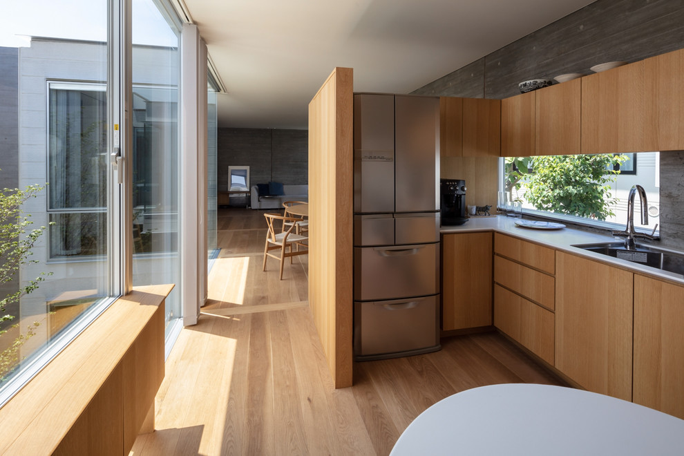 Moderne Küche mit flächenbündigen Schrankfronten, hellbraunen Holzschränken, braunem Holzboden, Halbinsel und braunem Boden in Tokio