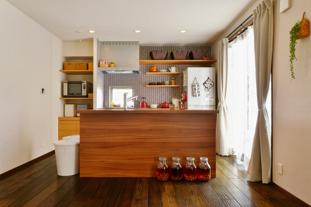 Idées déco pour une petite cuisine parallèle campagne en bois brun avec un évier 1 bac, un placard à porte plane, un plan de travail en bois, parquet foncé, îlot et un sol marron.