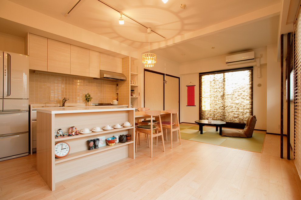 Ejemplo de cocina asiática grande abierta con armarios con paneles lisos, salpicadero beige, suelo de madera clara y una isla