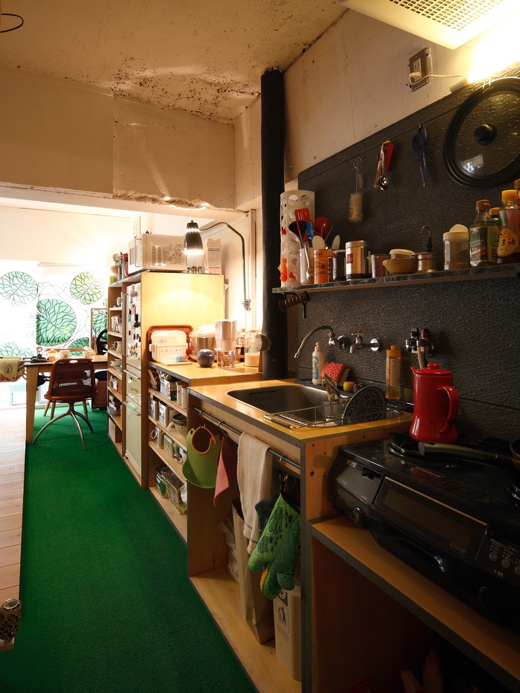 Ejemplo de cocina comedor lineal industrial con fregadero encastrado, armarios abiertos, puertas de armario de madera oscura, electrodomésticos negros y moqueta