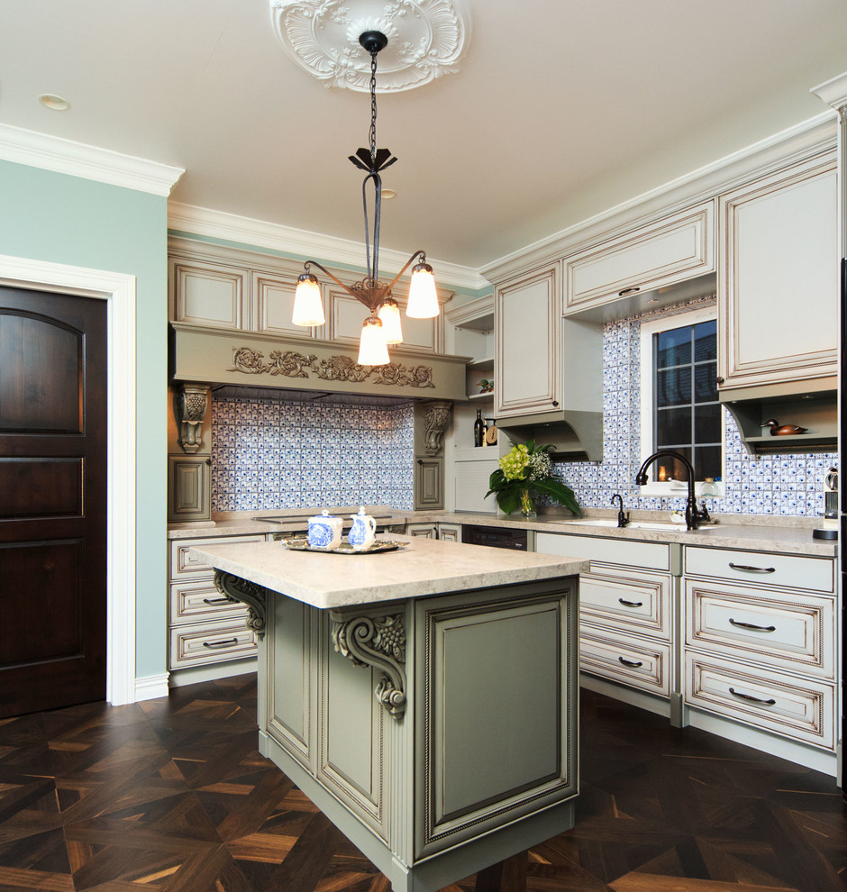 Klassisk inredning av ett stort kök, med en undermonterad diskho, luckor med upphöjd panel, beige skåp, bänkskiva i onyx, blått stänkskydd, stänkskydd i glaskakel, svarta vitvaror, mellanmörkt trägolv och en köksö