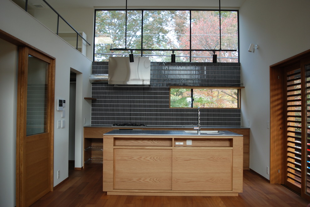 東京都下にある北欧スタイルのおしゃれなキッチン (一体型シンク、ベージュのキャビネット、ステンレスカウンター、ベージュキッチンパネル、木材のキッチンパネル、シルバーの調理設備、無垢フローリング、茶色い床) の写真