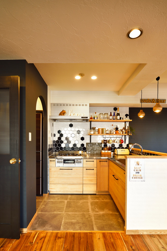 На фото: угловая кухня в современном стиле с плоскими фасадами, светлыми деревянными фасадами, столешницей из нержавеющей стали, разноцветным фартуком и серым полом без острова с