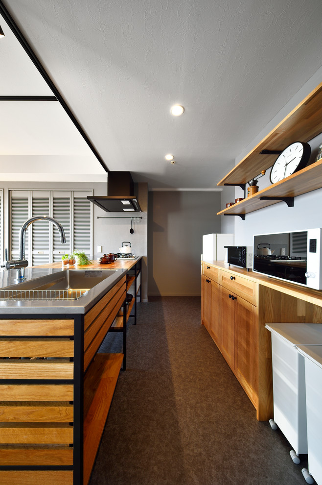 Foto di una cucina ad ambiente unico industriale con lavello a vasca singola, ante con riquadro incassato, ante in legno scuro, top in legno, penisola e pavimento grigio