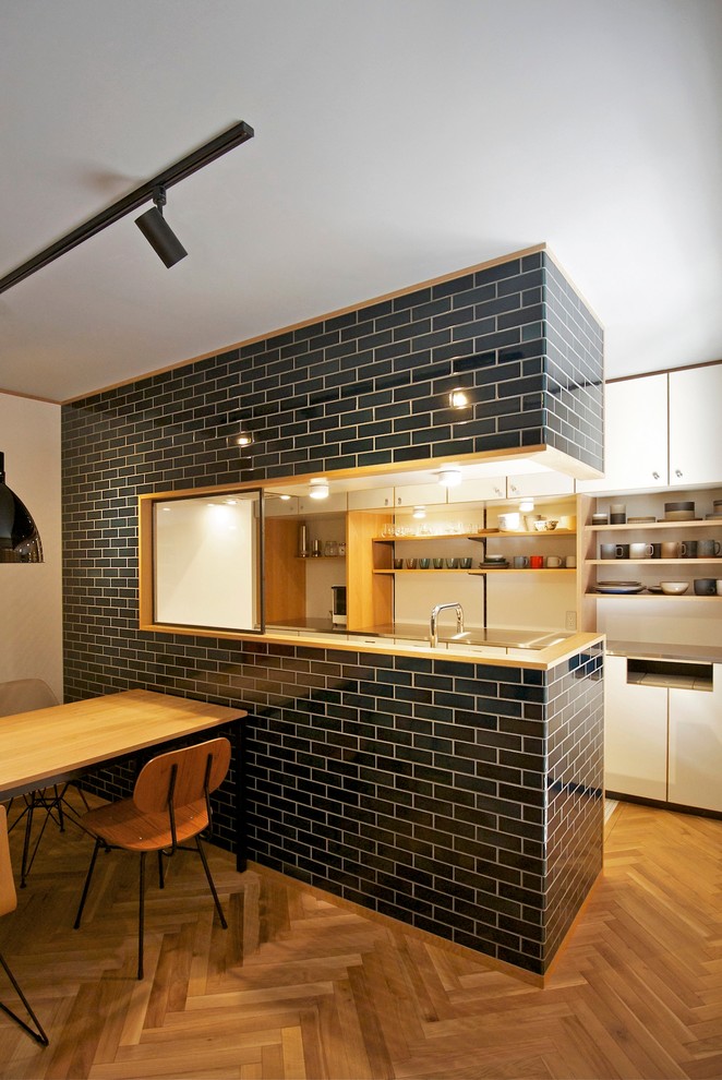 Foto di una cucina design con ante bianche, ante lisce, top in acciaio inossidabile, paraspruzzi bianco e pavimento in legno massello medio