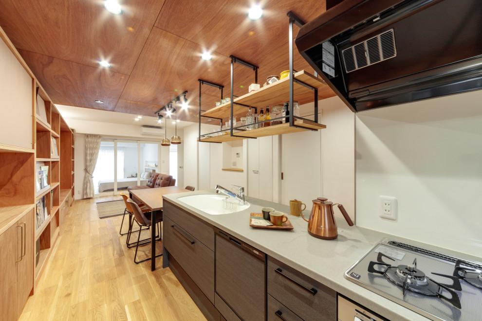 Example of a 1950s single-wall light wood floor, beige floor and shiplap ceiling open concept kitchen design in Other with an integrated sink, gray cabinets, solid surface countertops, white backsplash, stainless steel appliances and gray countertops