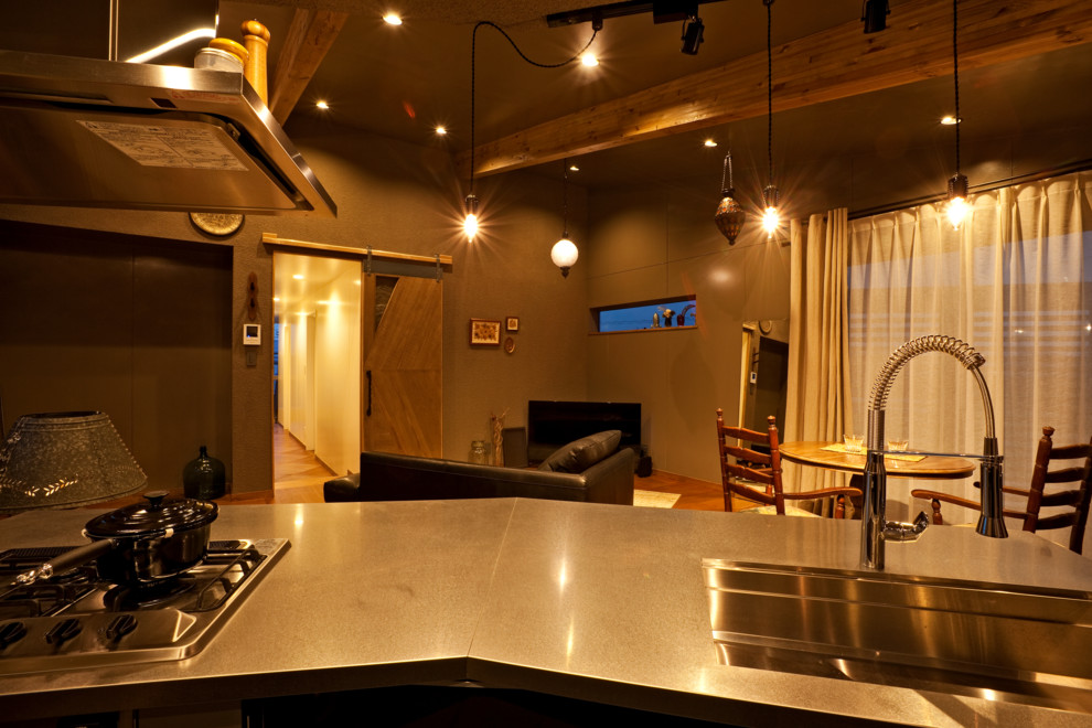 Inspiration för eklektiska kök med öppen planlösning, med en enkel diskho, bänkskiva i rostfritt stål, mellanmörkt trägolv, en köksö och brunt golv