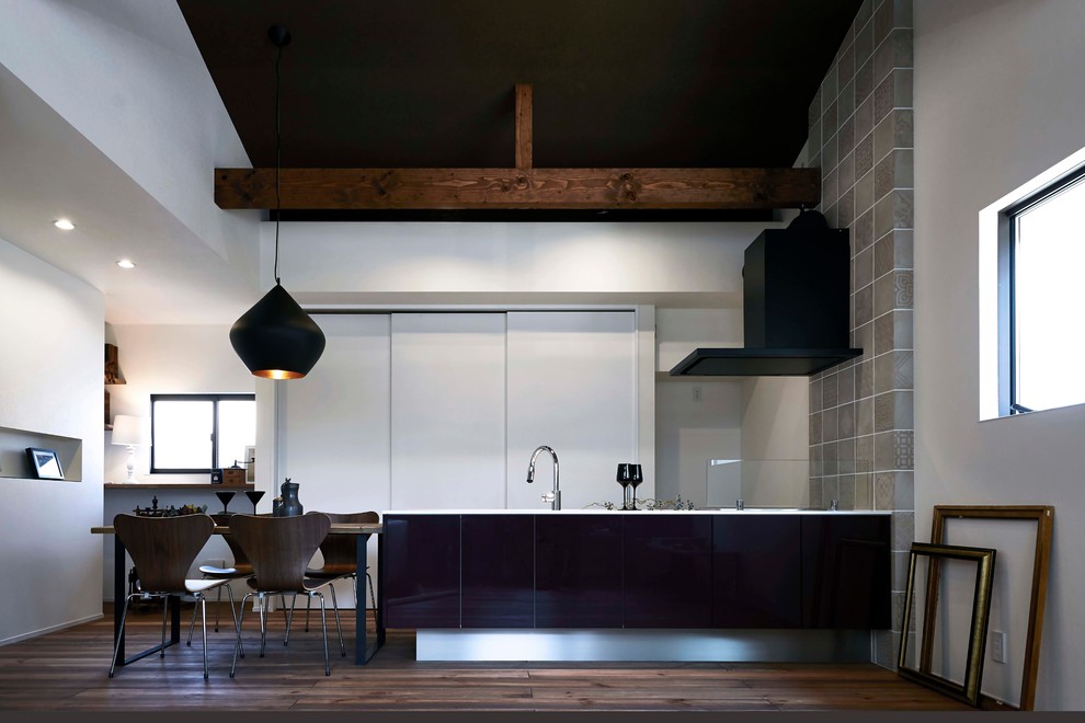 Cette photo montre une cuisine ouverte linéaire asiatique avec un évier intégré, un placard à porte plane, des portes de placard noires, parquet foncé, une péninsule et un sol marron.