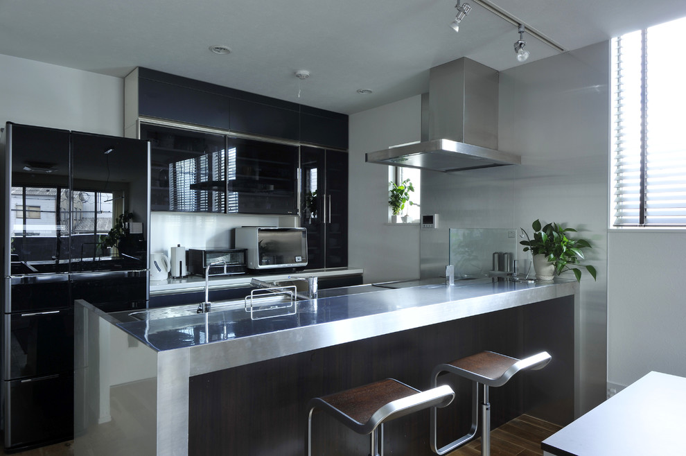 Diseño de cocina lineal actual abierta con fregadero integrado, encimera de acero inoxidable y península