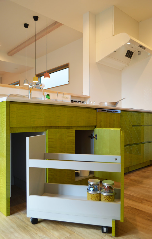 Diseño de cocina lineal escandinava abierta con puertas de armario verdes, encimera de granito, electrodomésticos de acero inoxidable, suelo de madera clara y suelo beige