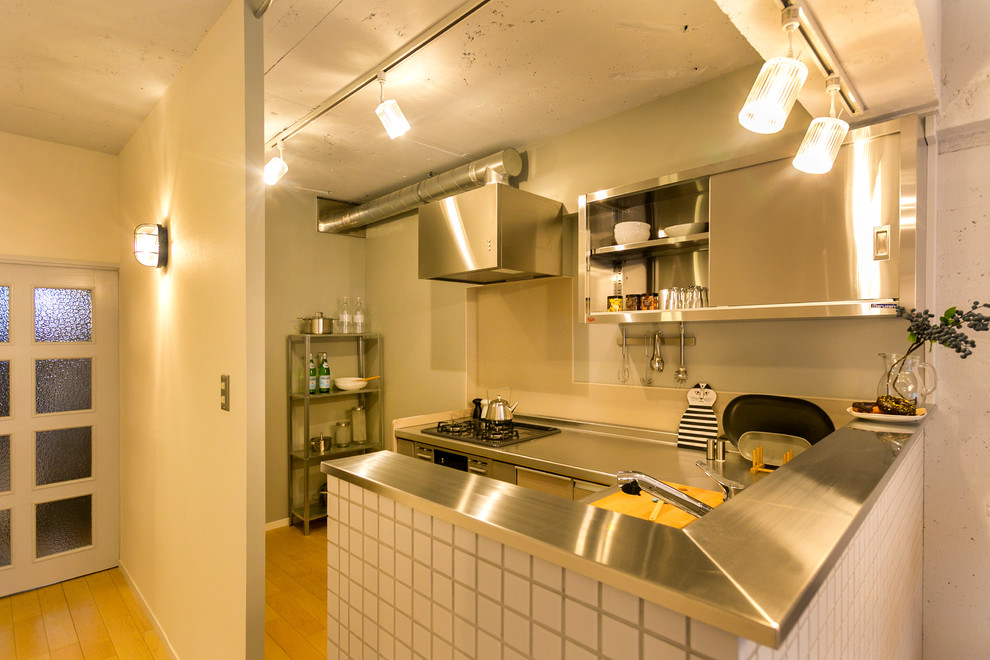 他の地域にある小さな北欧スタイルのおしゃれなキッチン (フラットパネル扉のキャビネット、ステンレスキャビネット、ステンレスカウンター、淡色無垢フローリング、茶色い床) の写真