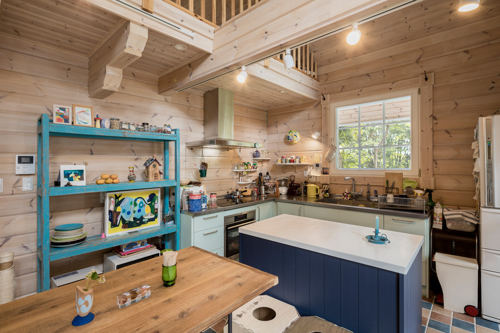 Rural l-shaped open plan kitchen in Other with a single-bowl sink, flat-panel cabinets, turquoise cabinets, stainless steel worktops, brown splashback, wood splashback, ceramic flooring, an island and multi-coloured floors.
