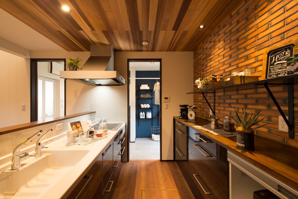 На фото: прямая кухня в восточном стиле с монолитной мойкой, плоскими фасадами, коричневыми фасадами, белым фартуком, паркетным полом среднего тона, полуостровом, коричневым полом и коричневой столешницей с