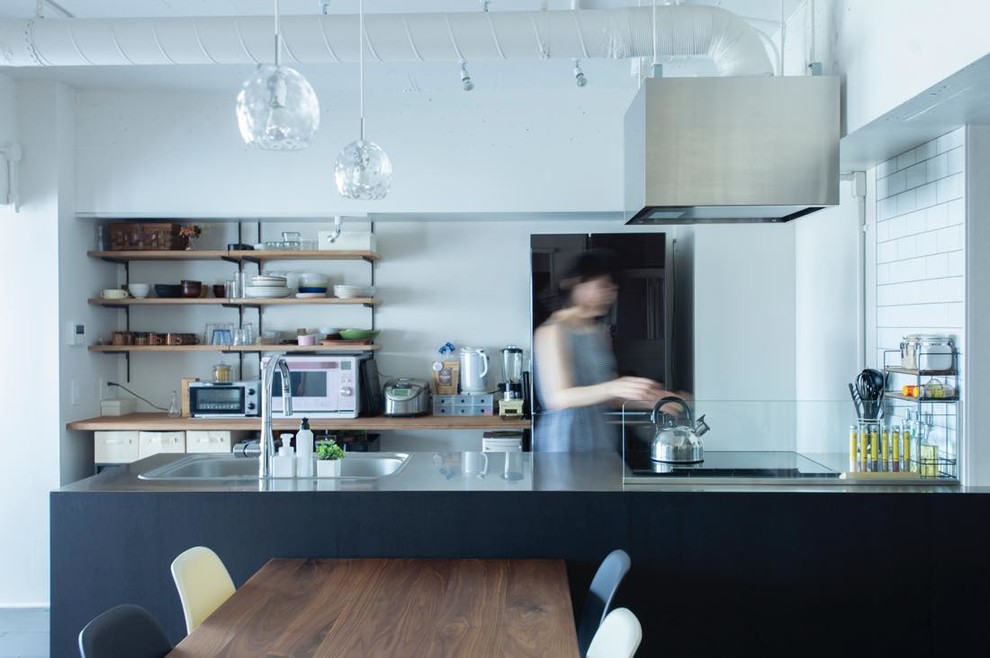 На фото: прямая кухня в стиле лофт с монолитной мойкой, столешницей из нержавеющей стали и полуостровом с