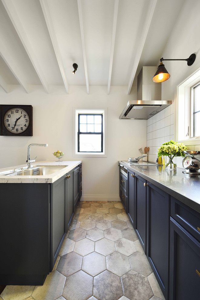 Retro Wohnküche mit Waschbecken, Schrankfronten mit vertiefter Füllung, schwarzen Schränken, Edelstahl-Arbeitsplatte, Küchenrückwand in Weiß, Kücheninsel und grauem Boden in Sonstige