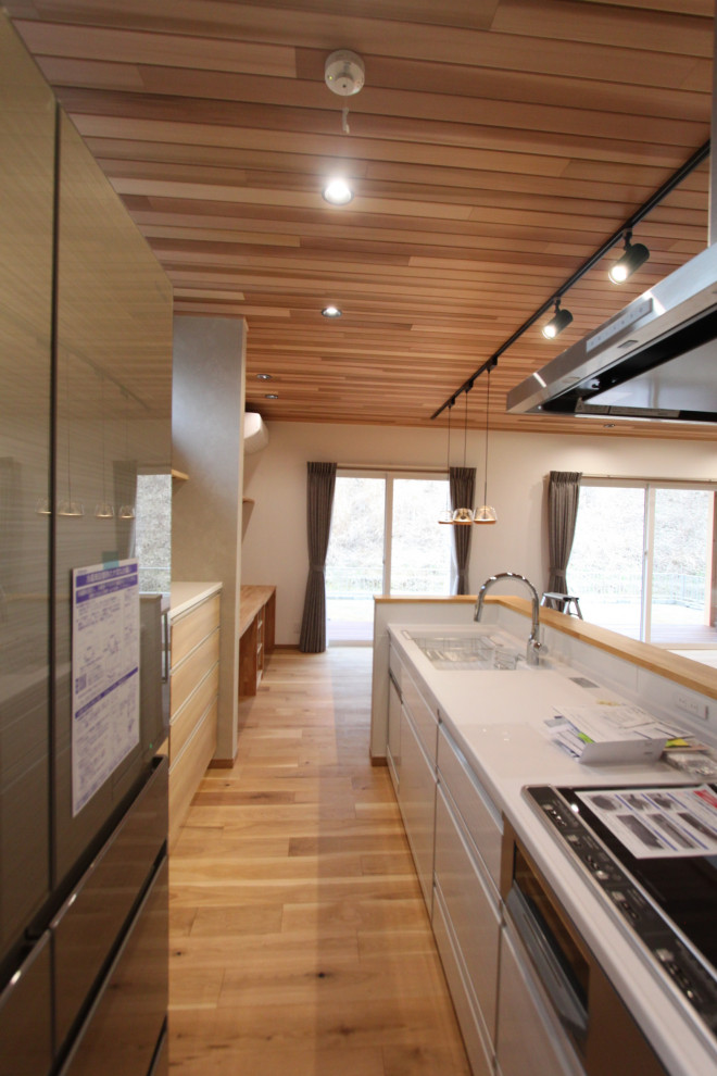 Exempel på ett retro vit linjärt vitt kök med öppen planlösning, med vita skåp, vitt stänkskydd, ljust trägolv, en köksö och beiget golv