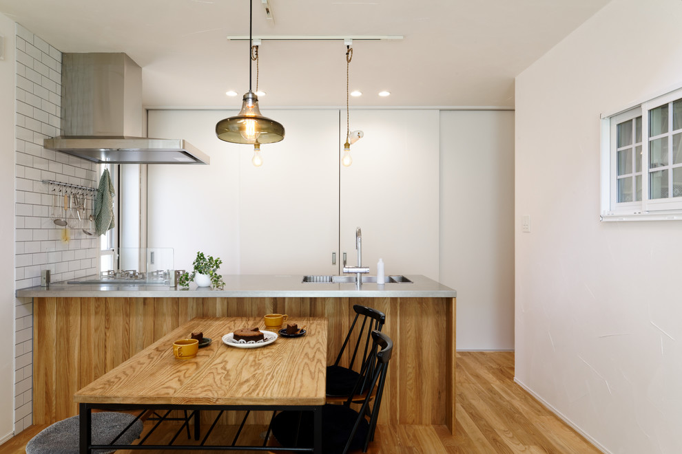 This is an example of a scandi kitchen in Other with a single-bowl sink, stainless steel worktops, medium hardwood flooring, an island and brown floors.