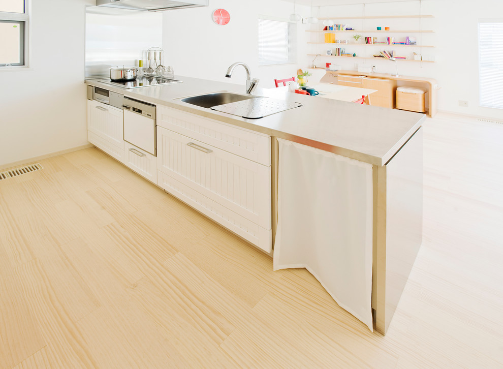 札幌にあるトランジショナルスタイルのおしゃれなキッチン (インセット扉のキャビネット、白いキャビネット、淡色無垢フローリング、一体型シンク、白いキッチンパネル、シルバーの調理設備) の写真