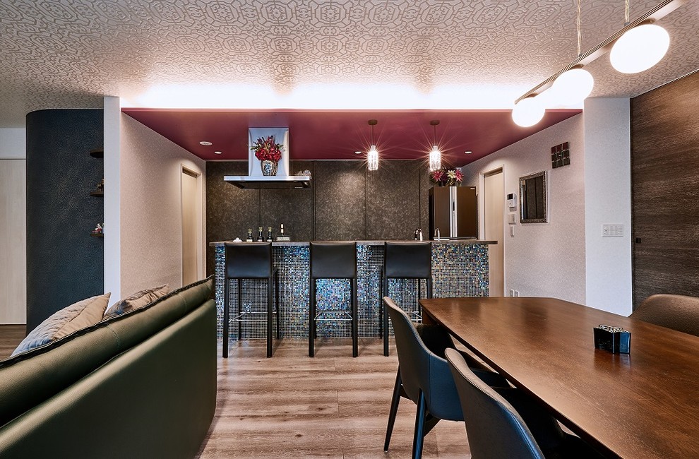 Modern inredning av ett avskilt linjärt kök, med en enkel diskho, skåp i slitet trä, rostfria vitvaror, plywoodgolv, en köksö och brunt golv