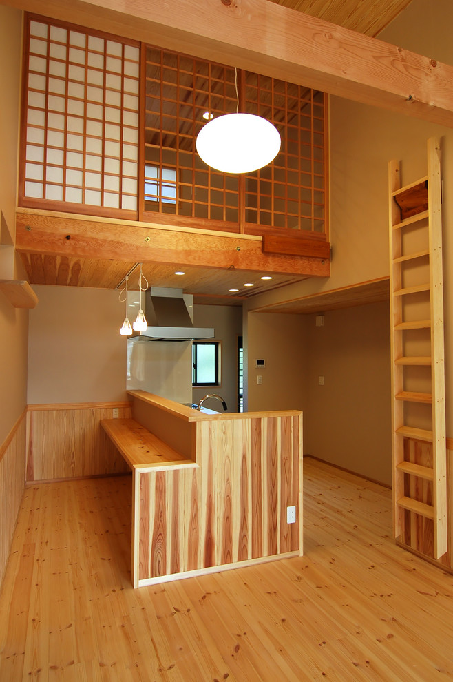Asiatisk inredning av ett linjärt kök med öppen planlösning, med bänkskiva i rostfritt stål, vitt stänkskydd, glaspanel som stänkskydd, ljust trägolv och beiget golv