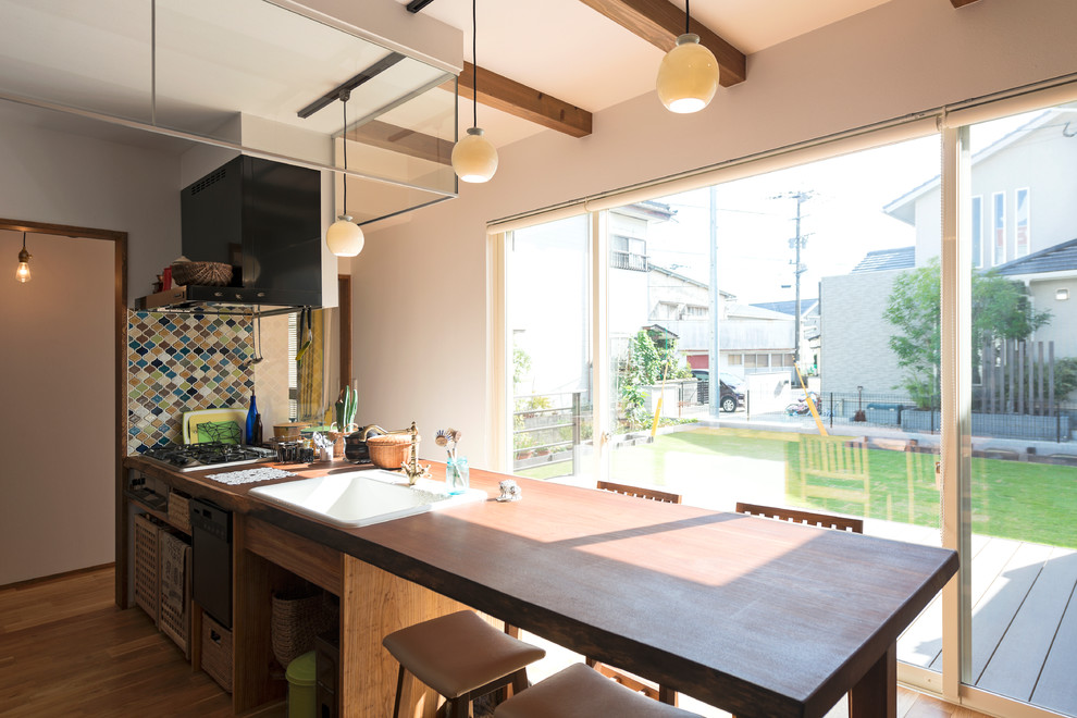Cette photo montre une cuisine ouverte asiatique avec un évier posé, un plan de travail en bois, un sol en bois brun, îlot et un sol marron.
