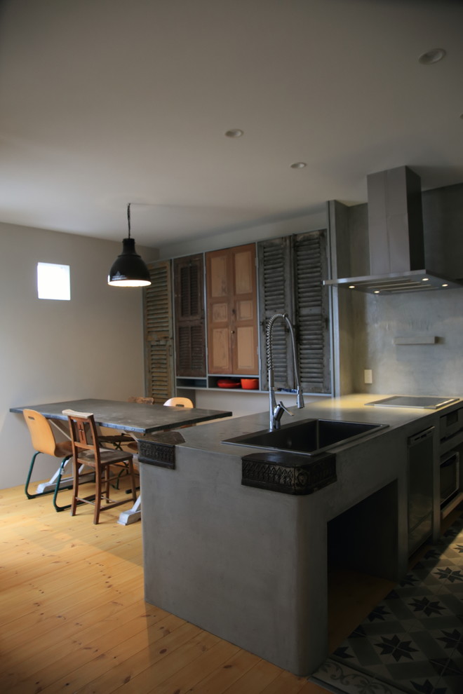 Industrial kitchen in Other with a built-in sink, integrated appliances, light hardwood flooring and a breakfast bar.
