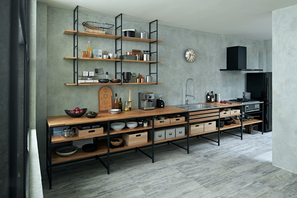 Foto på ett industriellt linjärt kök, med en enkel diskho, öppna hyllor, träbänkskiva, grått stänkskydd, svarta vitvaror, en halv köksö och grått golv