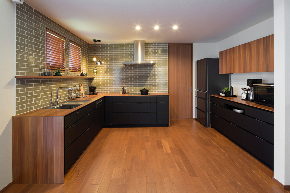 This is an example of a scandi l-shaped open plan kitchen with a submerged sink, beaded cabinets, black cabinets, stainless steel appliances, no island, brown floors and medium hardwood flooring.