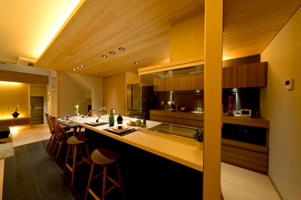 Diseño de cocina comedor lineal asiática con armarios con paneles lisos, puertas de armario de madera oscura, una isla y suelo negro