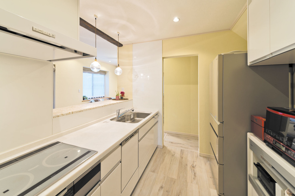 Foto på ett funkis vit linjärt kök med öppen planlösning, med en enkel diskho, släta luckor, vita skåp, bänkskiva i koppar, vitt stänkskydd, rostfria vitvaror, ljust trägolv, en halv köksö och beiget golv