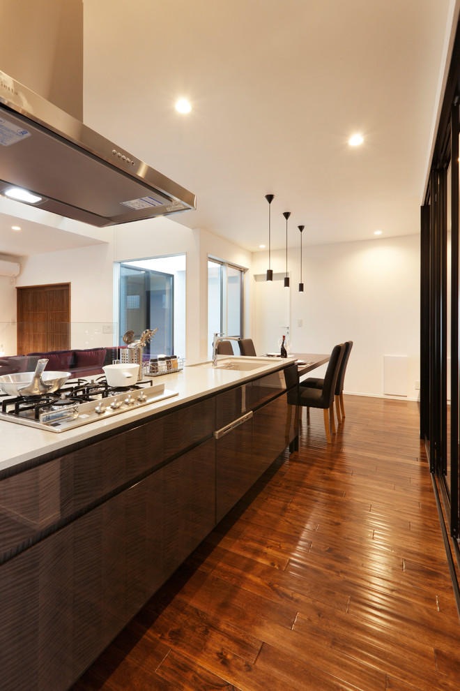 Idéer för orientaliska linjära kök med öppen planlösning, med grå skåp, granitbänkskiva, rostfria vitvaror, mellanmörkt trägolv och brunt golv